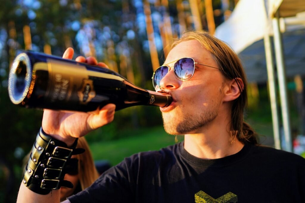 man wearing black crew-neck t-shirt drinking alcohol