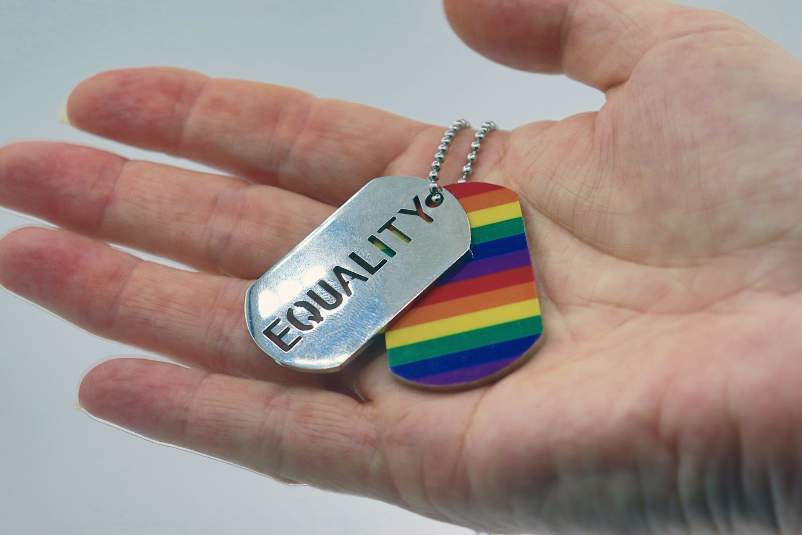 a person holding a rainbow dog tag in their hand